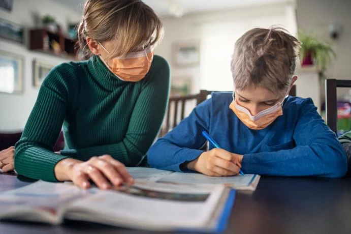 parent  and child home schooling each other with face masks