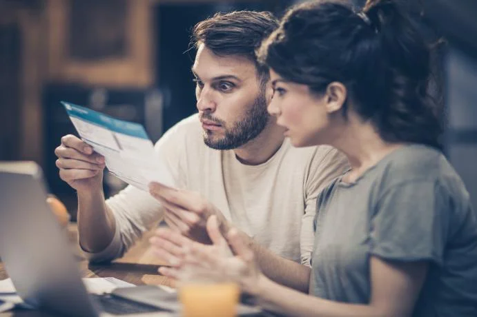couple looking at paper with concerned look on their faces