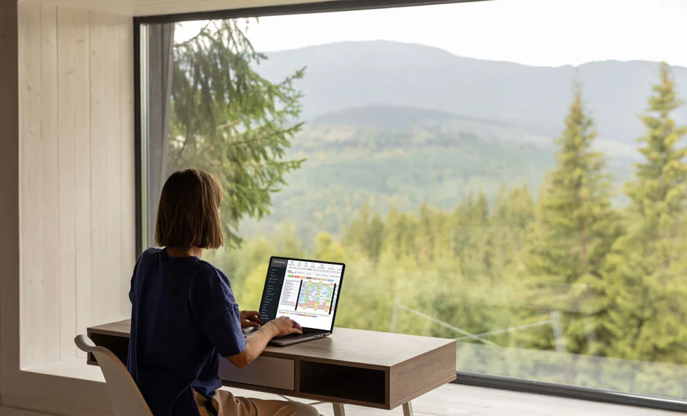 girl at a desk with laptop- trees outside