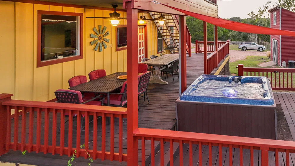 inn exterior with tables, chairs, and a hot tub