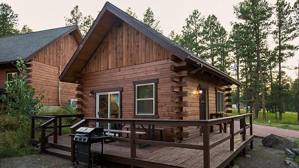 Two adjacent cabins with trees in the background