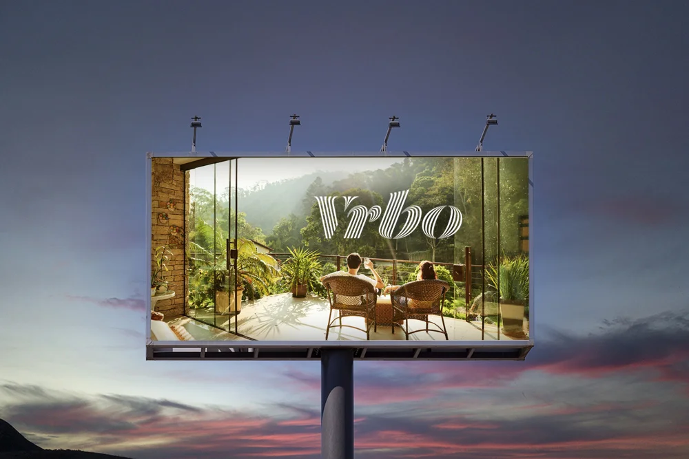 billboard with Vrbo logo over a picture of couple in vacation rental in the rain forest