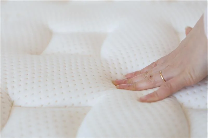 female hand presses on mattress