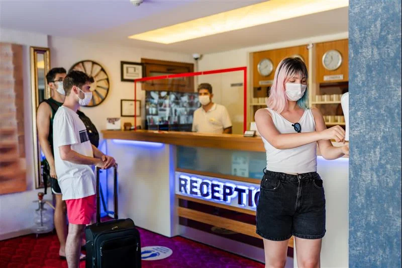 Three people stand at one side of the reception desk to check in, while another person checks them in