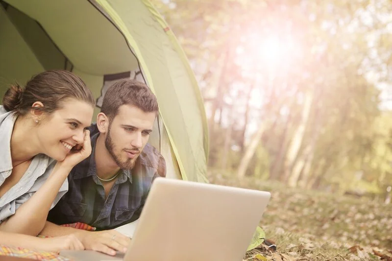 couple looking at a computer in a tent